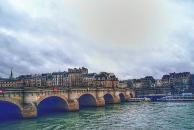 Bridge over river in city against sky