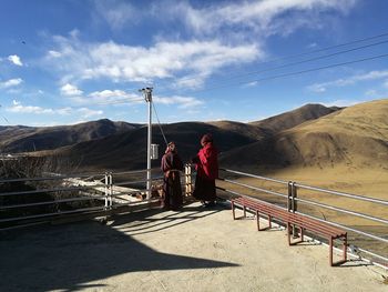 Men standing on railing against mountain range