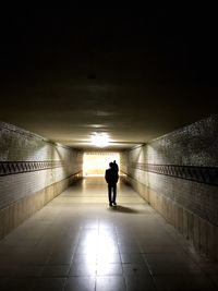 Rear view of silhouette man standing in illuminated tunnel