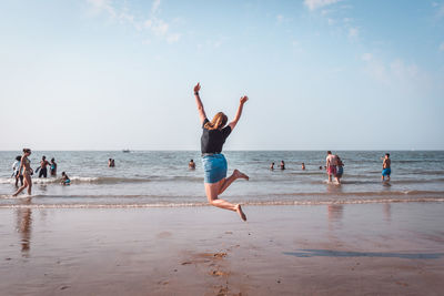 People enjoying at beach against sky