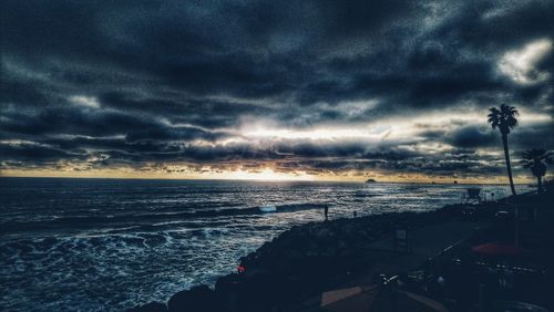 Scenic view of sea against dramatic sky during sunset