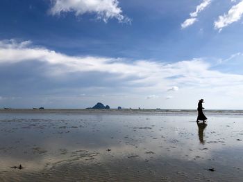 Local people while find a clam on the beach under sunny blue sky.