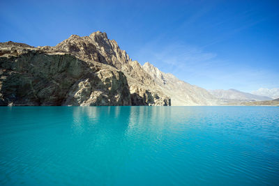 Scenic view of sea and mountains against blue sky