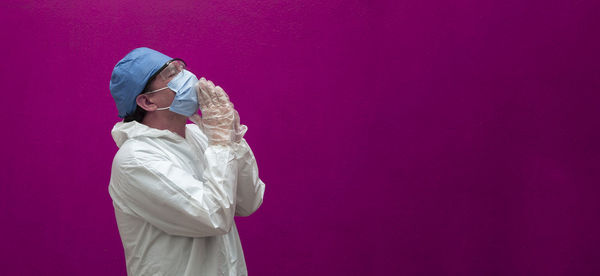 Midsection of woman standing against pink wall