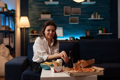 Portrait of young woman using mobile phone while sitting in cafe