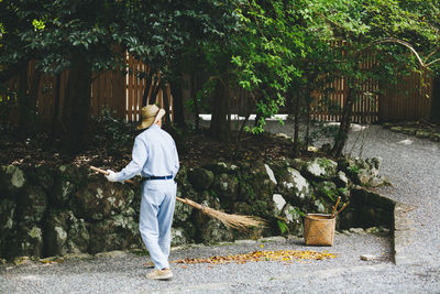 Rear view of man sweeping on footpath