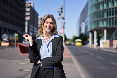 Portrait of young woman standing in city