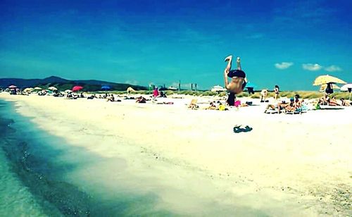 People at beach against blue sky