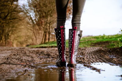 Low section of woman walking on dirt road