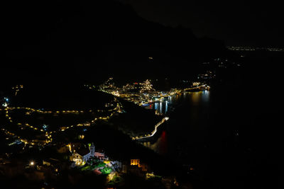 High angle view of illuminated city by sea against sky