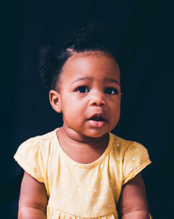 Portrait of cute baby boy against black background