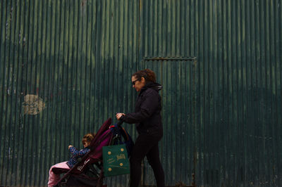 Side view of young woman standing against wall