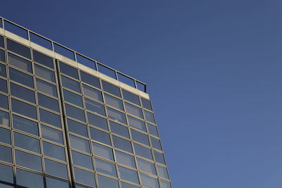 Low angle view of modern building against clear blue sky