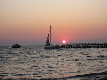 Sailboat sailing on sea against sky during sunset