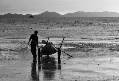 Rear view of man with boat at beach