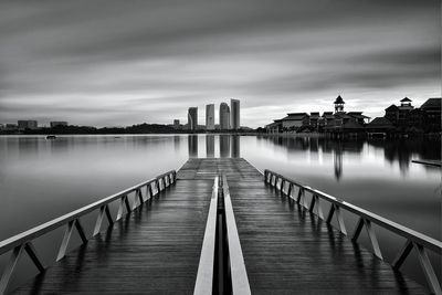 Pier over lake against sky in city