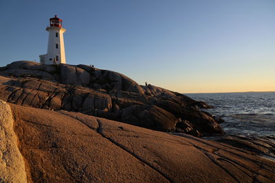 Lighthouse by sea against sky