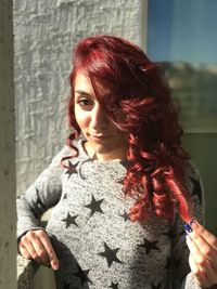 Portrait of beautiful young woman standing against red wall