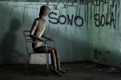 Man sitting on chair in abandoned room