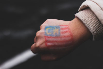 Cropped hand with malaysian flag tattoo