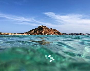 Surface level of rocks by sea against sky