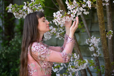 Midsection of woman standing by flowering plants