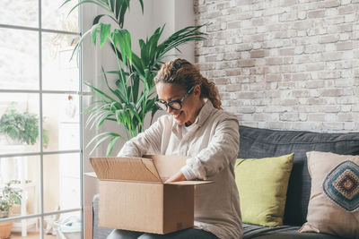 Young woman using phone while sitting on sofa at home