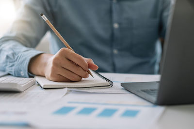 Midsection of man writing in diary