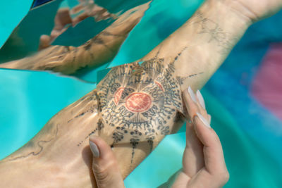 Cropped image of woman with prism on tattoo underwater