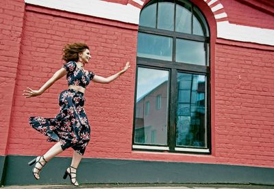 Smiling young woman against building