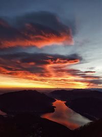 Scenic view of dramatic sky over silhouette mountains during sunset