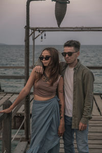 Portrait of young woman wearing sunglasses while standing at beach