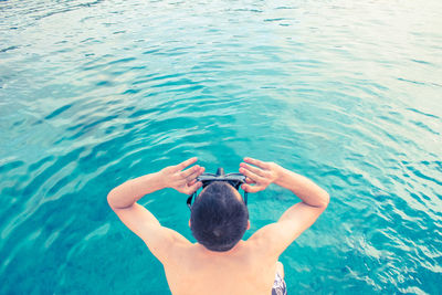 Rear view of shirtless man swimming in pool