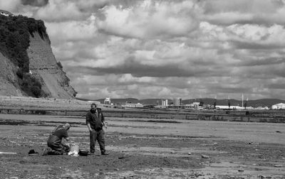 Woman standing on beach against cloudy sky