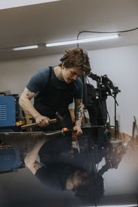 Blacksmith using hammer and anvil in workshop