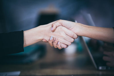 Cropped image of businesswomen shaking hands in office