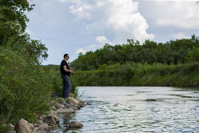 Full length of young man by lake against sky