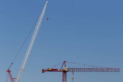 Two construction cranes against blue sky