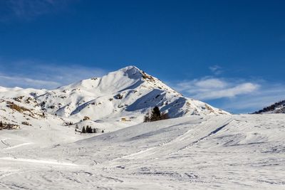 Scenic view of snowcapped mountains against blue sky