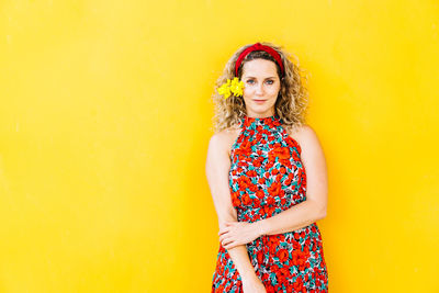 Portrait of a smiling young woman against yellow wall