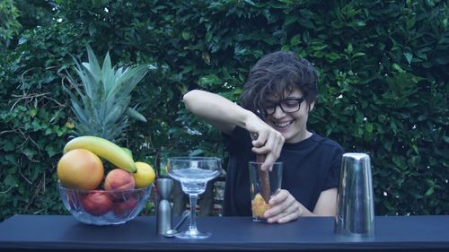 Smiling young woman preparing juice against plants