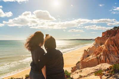 Rear view of couple on beach against sky