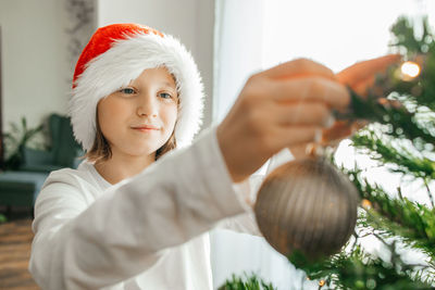 Happy teenage girl decorates the christmas tree at home on the eve of the holidays. 