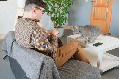 Side view of young man sitting on sofa at home