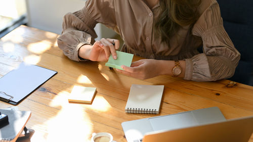 Hands of woman removing adhesive note at desk