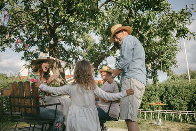 Family applauding while looking at senior man and girl dancing during garden party