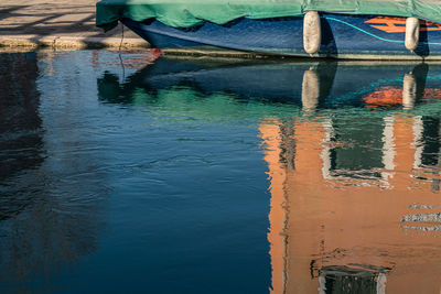 Boat moored in canal with reflections on water