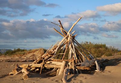 Stack of logs on field against sky