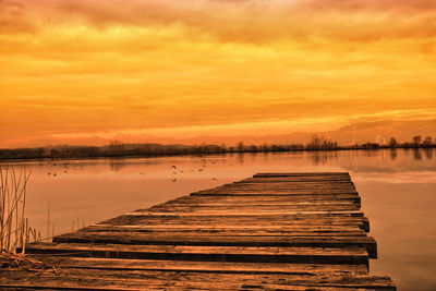 Pier over lake against sky during sunset