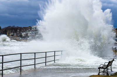 Waves splashing on shore against sky